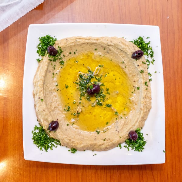 Baba Ghanoush with a pool of olive oil, garnished with parsley and black olives.